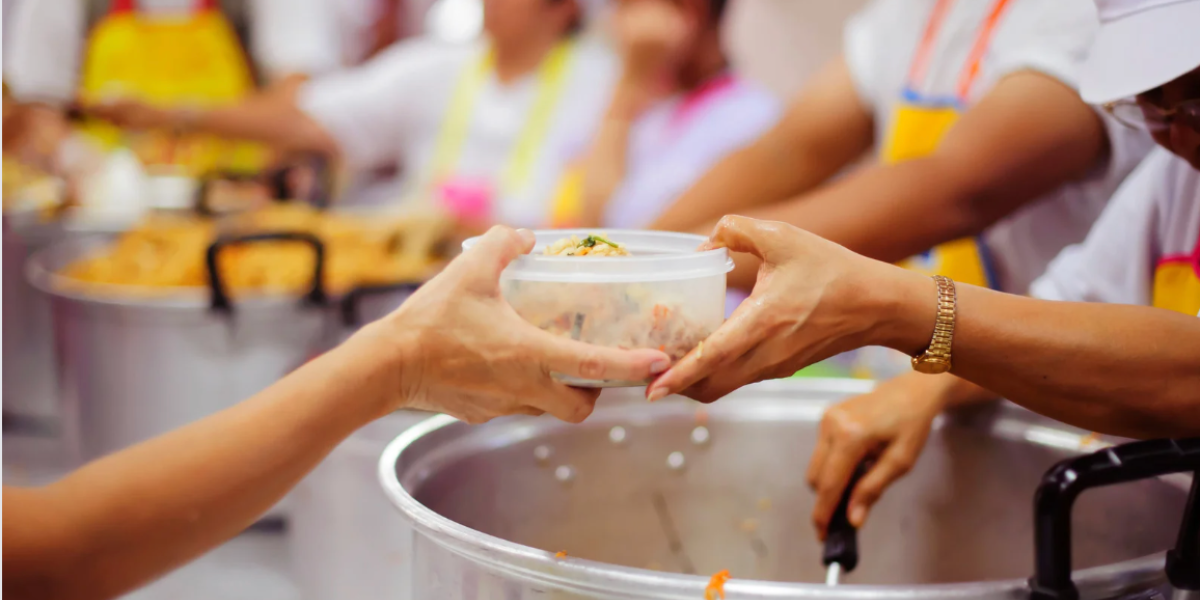 Hands passing Tupperware with food at soup kitchen