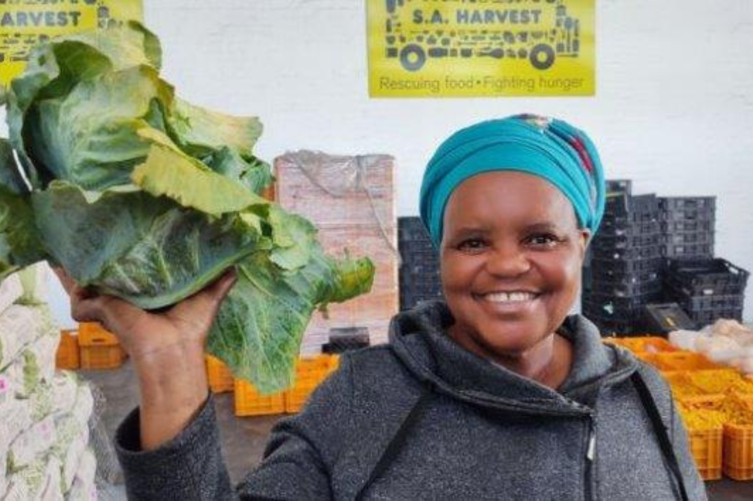 Smiling volunteer holds up a cabbage going to a family in need