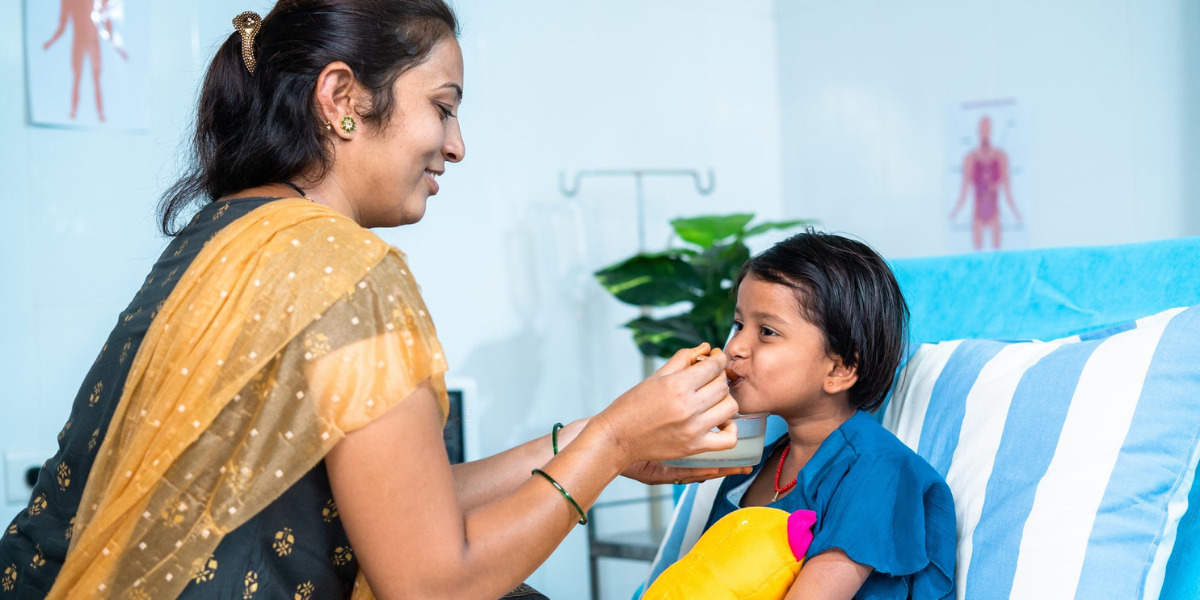 A mother feeding a child in a hospital bed - A Changing Philanthropic Landscape in India