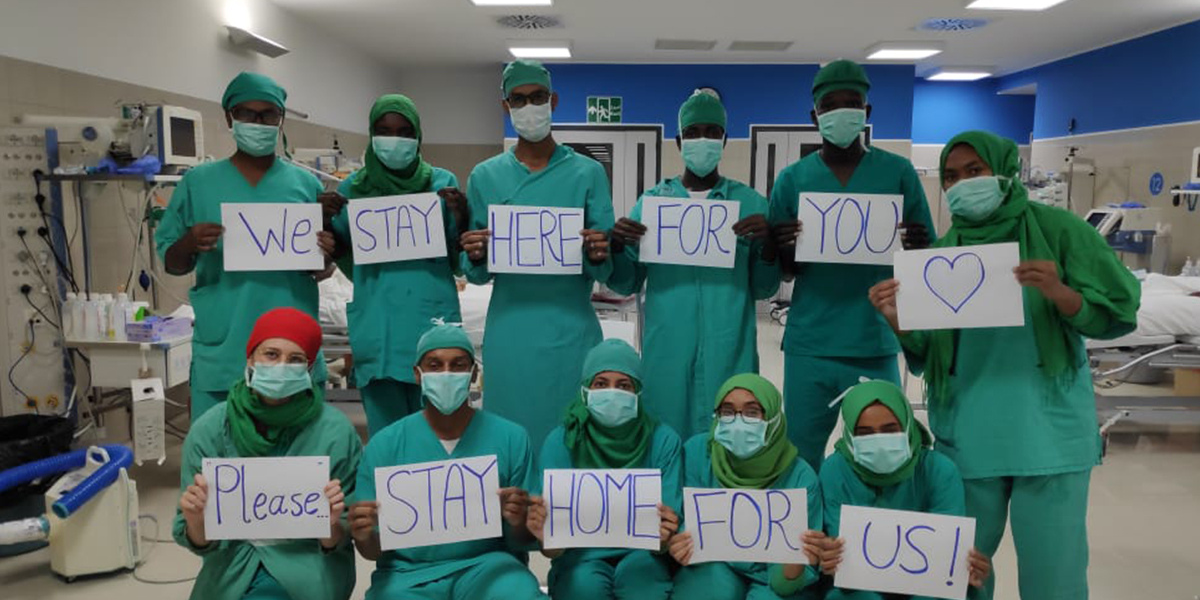 EMERGENCY USA medical staff during COVID-19 holding signs that read We stay here for you (heart), please stay home for us! - Answering the Call