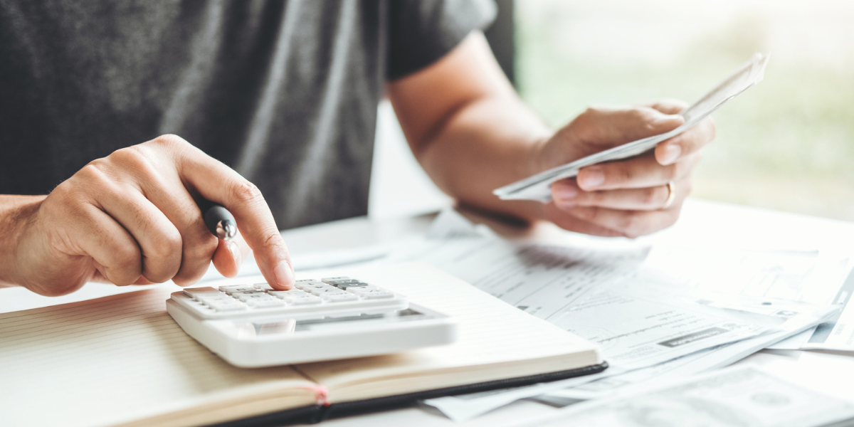 Person using calculator and handling documents - How the CARES Act, as supplemented by the Consolidated Appropriations Act of 2021, Impacts Charitable Giving